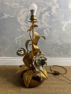 a lamp that is on top of a wooden base with flowers and leaves around it