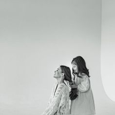 two women standing next to each other in front of a white background