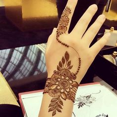 a woman's hand with henna tattoos on it, and a flower design on the wrist