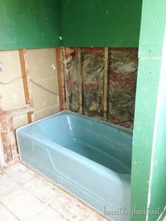 a bath tub sitting inside of a bathroom next to a wall with insulation on it