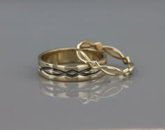 two gold wedding rings sitting side by side on a reflective surface, with one ring in the shape of a cross