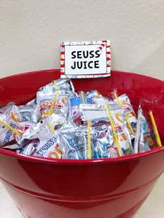 a red bowl filled with lots of gummy bears and candy bar wrappers next to a sign that says seuss juice