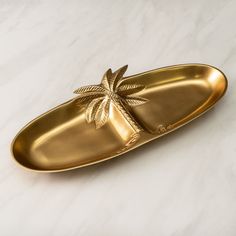 a gold plate with a palm tree on it sitting on a marble countertop next to a white wall