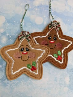 two gingerbread christmas ornaments hanging from twine on blue and white snowflakes