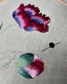 a close up of a piece of cloth with flowers on it and a needle in the middle