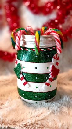 a green and white jar with candy canes in it sitting on a furry surface