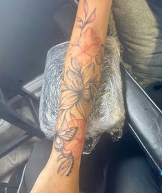 a woman's arm with flowers on it and a tattoo on the other side