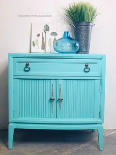 a blue dresser with two drawers and a potted plant sitting on top of it