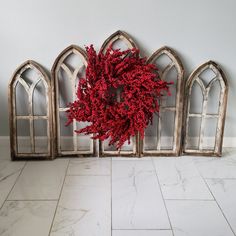 a bunch of red flowers sitting on top of a white floor next to arched windows