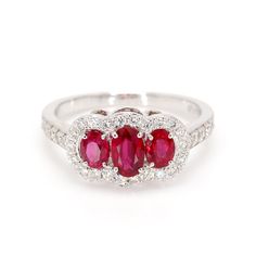 Classic ruby 3-stone ring in 14 karat white gold. This ring is prong set with three 1.30cttw red oval shaped ruby corundum, and 42 diamonds weighing 0.52cttw. Ring Size 7. Ruby Is The Birth Stone For July. Classic Red Three Stone Rings, Red Three Stone Diamond Ring For Promise, Red Three Stone Diamond Promise Ring, Oval Ruby Ring With Three Diamonds, Oval Red Ruby Ring With Three Stones, Oval Three Stone Ruby Ring With Diamonds, Classic Red Three Stone Diamond Ring, Red Three-stone Diamond Promise Ring, Classic Red Three-stone Ring