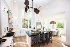 a large kitchen with white cabinets and black counter tops, along with an island in the middle