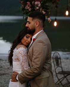 a man and woman embracing each other in front of a lake