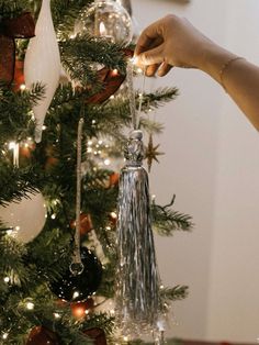 someone decorating a christmas tree with ornaments