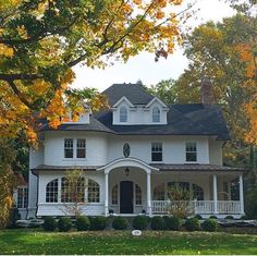 a large white house sitting in the middle of a lush green field with lots of trees