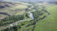 an aerial view of a river running through a lush green valley