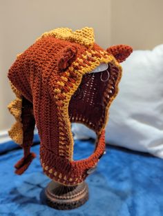 a crocheted hat with an open mouth on top of a table next to a pillow