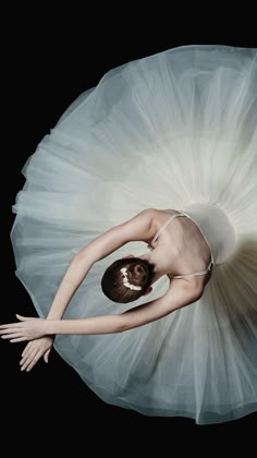 a ballerina in white tutu with her arms stretched out