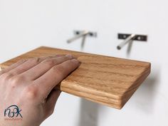 a person's hand is on the edge of a wooden shelf