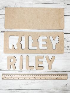 the word riley written in cutout letters next to a ruler on a white wooden surface