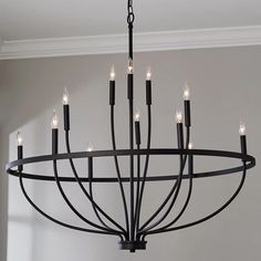 a black chandelier with candles hanging from it's centerpiece in a room