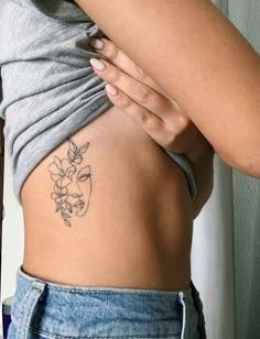 a woman with a flower tattoo on her lower back and the upper half of her stomach