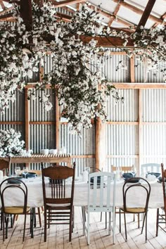 the table is set with white linens and wooden chairs in front of an old - fashioned wood paneled wall