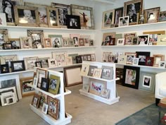 a room filled with lots of framed pictures on the wall and shelves full of photos