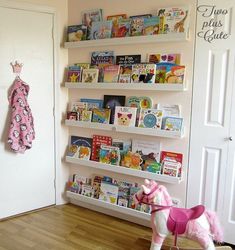 a toy horse is standing in front of a book shelf filled with children's books