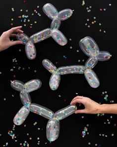 three clear balloons with confetti on them and some sprinkles around them