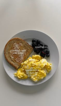 a white plate topped with eggs, toast and berries