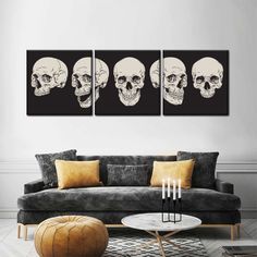 three skulls on black and white canvases in a living room with grey sofas