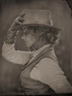 an old photo of a woman wearing a hat and holding her hand on her head