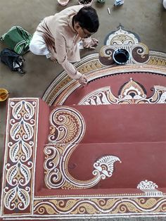 a man is working on an intricately painted bench in the middle of a building