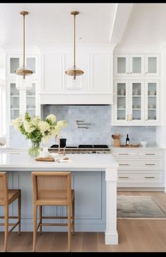 a kitchen with white cabinets and wooden chairs