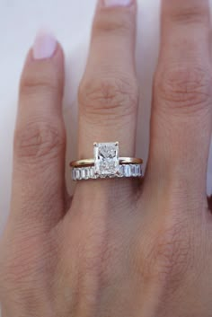 a woman's hand with a diamond ring on top of her finger and the other hand holding an engagement ring