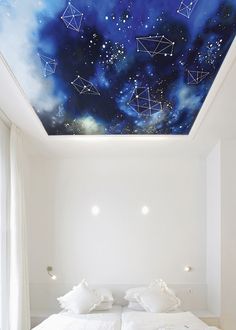 the ceiling is painted with blue and white stars, while the bed has pillows on it