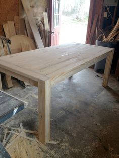 a wooden table sitting inside of a room next to a window with lots of wood on it