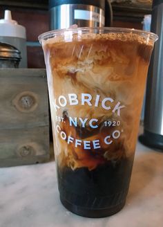 a plastic cup filled with liquid sitting on top of a counter next to a coffee maker