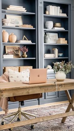 a wooden table with a laptop on it in front of bookshelves and shelves