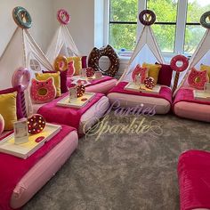 pink and yellow couches with donuts on them in front of large windows at a birthday party