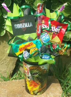 a bucket filled with candy and candies on top of a stone wall next to plants