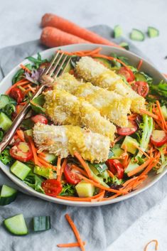 a salad with carrots, cucumbers and chicken on it is ready to be eaten