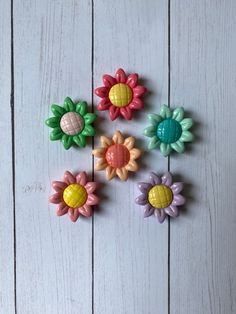 six small plastic flowers on a white wooden surface