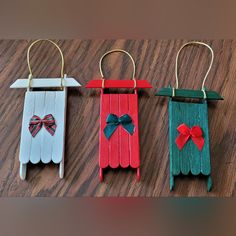 three small wooden tags with bows on them hanging from clothes pins and clips attached to strings