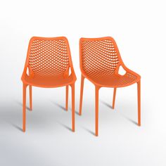 two orange chairs sitting next to each other on a white surface and one chair has a hole in the back