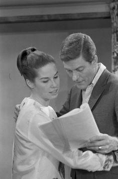 a man standing next to a woman holding a book