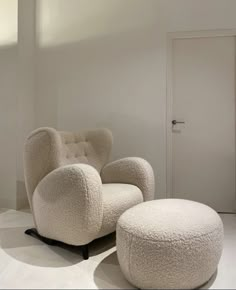 a large white chair and ottoman in a room with an open door on the other side