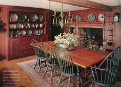 a dining room table and chairs with plates on the wall above it, in front of a fireplace