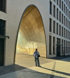 a man standing in front of a building with a large arched doorway on the side