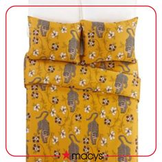 a yellow comforter with monkeys and flowers on the bottom, along with two pillows